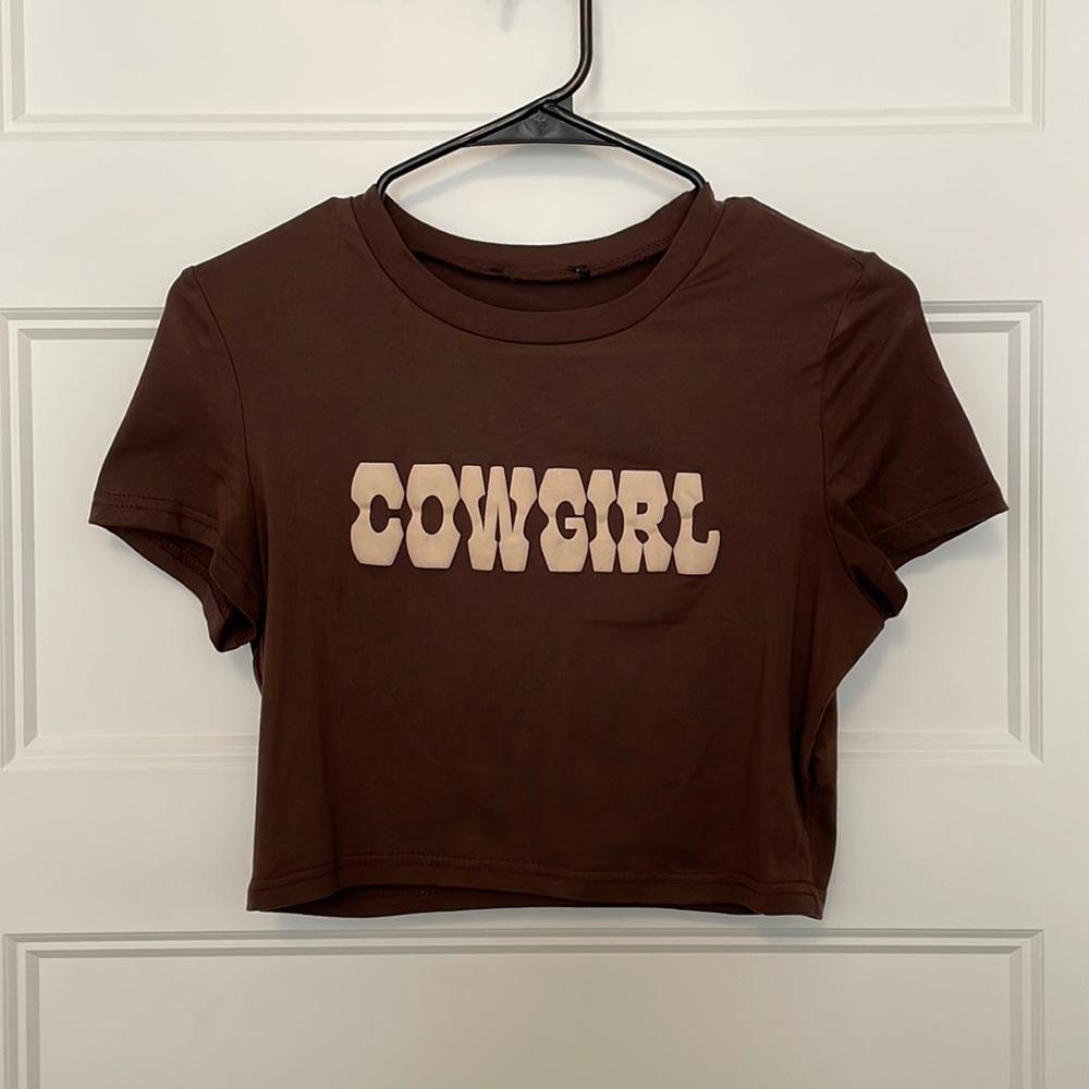 Brown cropped short sleeve t-shirt with “cowgirl” written across.